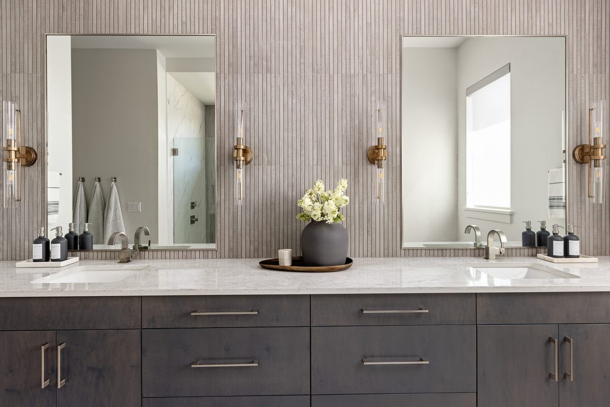 Vertical fluted feature wall with brass sconces above a vanity