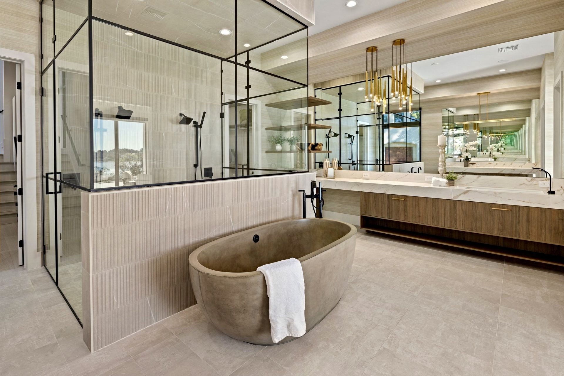 Luxury master bathroom with fluted porcelain feature wall, large-format tile floor, glass shower enclosure, and sculptural freestanding tub