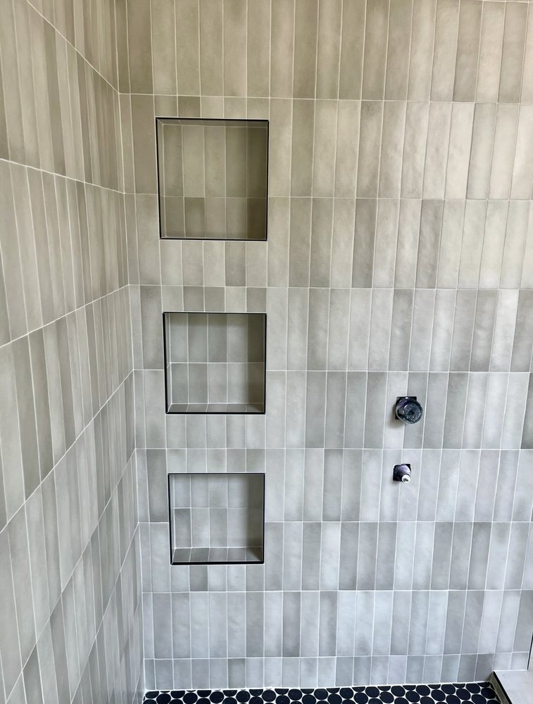 Shower wall under construction showing three recessed tile niches set plumb and valve rough-ins before glass installation