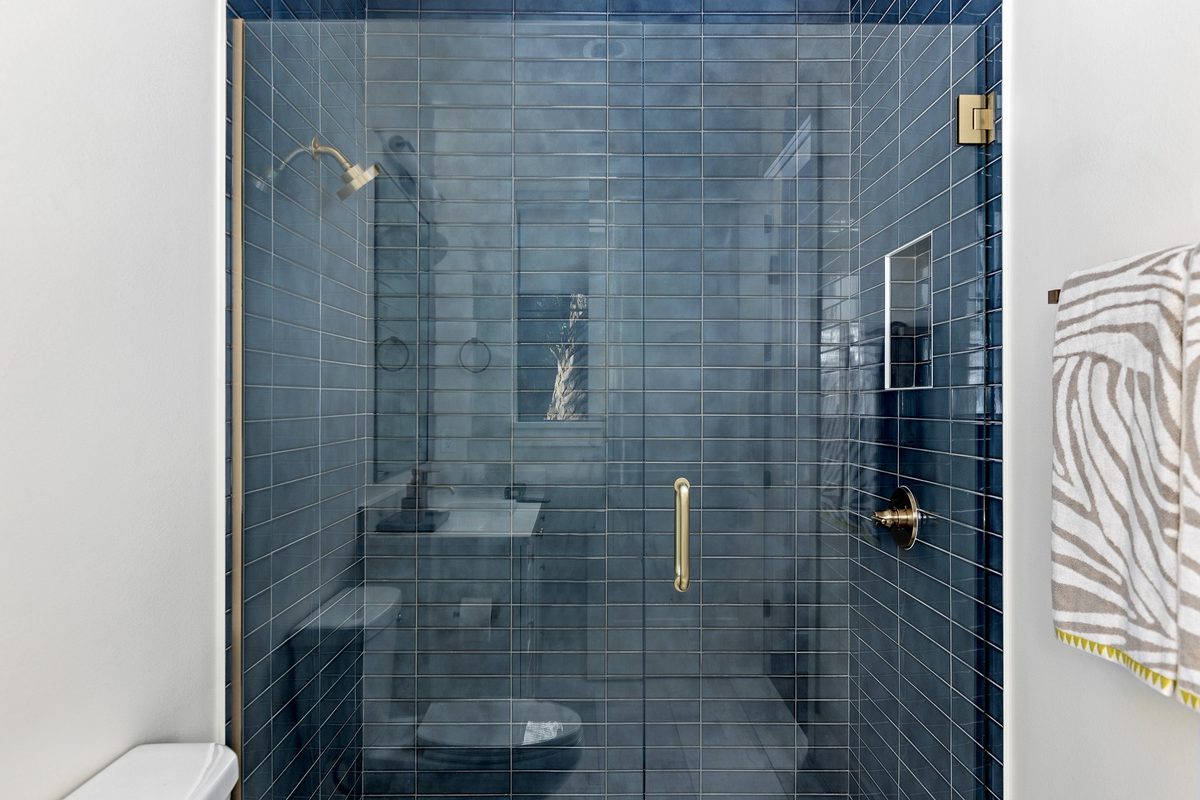 Walk-in shower with deep-blue stacked tile and brass fixtures